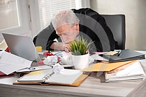 Overworked businessman sitting at a messy desk