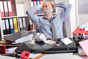 Overworked businessman sitting at a messy desk