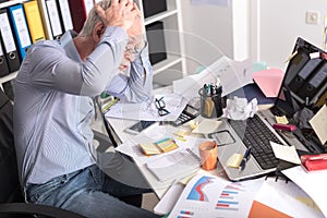 Overworked businessman sitting at a messy desk