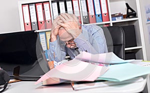 Overworked businessman sitting at a messy desk