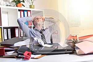 Overworked businessman sitting at a messy desk, light effect