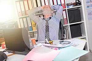 Overworked businessman sitting at a messy desk, light effect