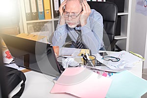 Overworked businessman sitting at a messy desk, light effect