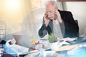Overworked businessman sitting at a messy desk; multiple exposure