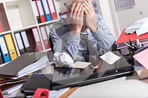 Overworked businessman sitting at a messy desk