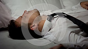 Overworked businessman sleeping on bed in suit, tiring busy work, lifestyle photo