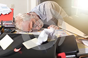 Overworked businessman sleeping on a messy desk, light effect