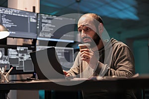Overworked coder drinking coffee cup and programming