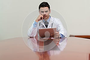 Overworked Doctor Sitting By His Desk