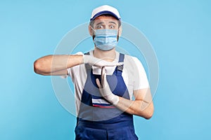 Overworked handyman in overalls and gloves showing time out gesture, need break. Profession of service industry