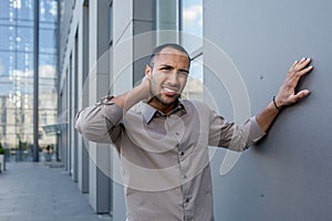 An overworked and overworked office worker, a man outside the office building has severe pain in his neck, injured a