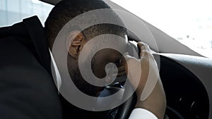 Overworked personal driver falling asleep on steering wheel of car, tired man