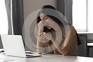 Overworked stressed asian business woman holding glasses feeling eye strain