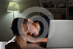 Overworked tired, Asian businessman sleeping while using computer working late at night at home