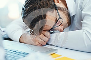 Overworked, tired and man sleeping on desk with burnout, fatigue and business employee with glasses, papers and laptop