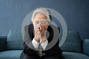 Overworked tired old lady holding head feeling headache. Asian senior business woman stress from hard work. Frustrated business