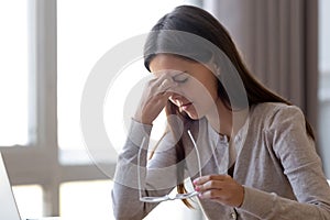 Overworked tired young woman student holding glasses feeling eye strain