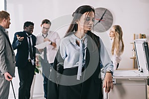 overworked untidy businesswoman standing near copier with blurred colleagues working on background