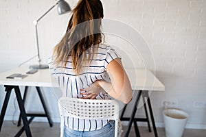 Overworked woman with back pain in office with bad posture