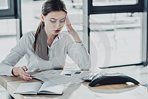 overworked young businesswoman with headache doing paperwork