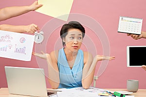 Overworked young employee refuses all things, frowns face in annoyance, sits at desktop with paper documents and notepad, isolated