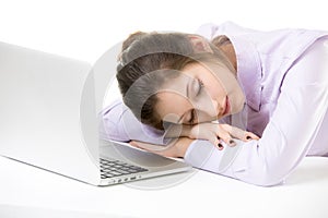 Overworked young woman sleeping in front of laptop
