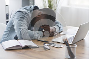 Exhausted black businessman napping at workplace in office