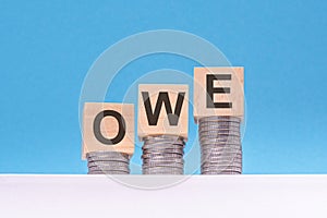 owe - text on wood cube block stack with coins
