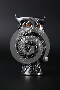 Owl a decorative figure, from different materials, against a dark background.