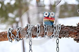 Owl made of wool on a tree branch which is wrapped in a chain