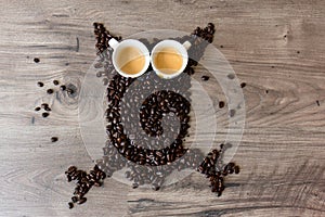 Owl shaped figure made out of coffee beans and two full espresso cups on top of a table