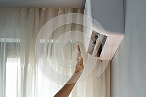 Apartment owner turns on air conditioner checking operating device reaching hand to air flow