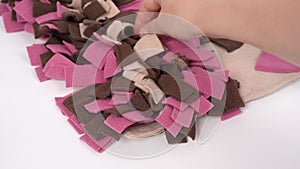 Owner checks and cleans a soft washable textile training snuffle mat for dogs nose work from wool and small debris