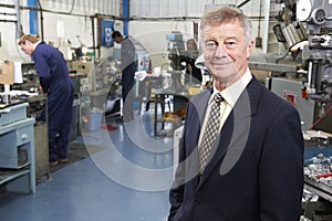 Owner Of Engineering Factory With Staff In Background