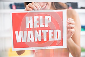 Owner Holding Help Wanted Sign In Retail Store