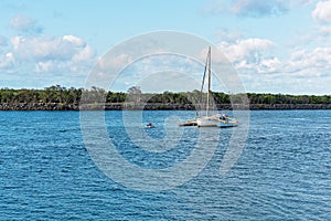 Owner Motoring Towards Moored Catamaran In River