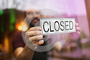 Owner puts closed sign at bar or restaurant window