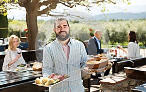 Owner of restaurant in open air meeting guests