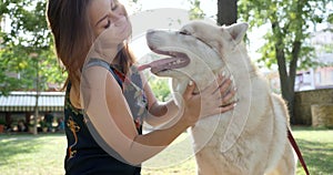 Owner stroking his pet in backlight outdoors, young woman hugs husky dog close-up