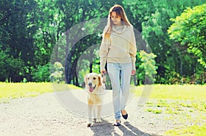 Owner woman walking with her Golden Retriever dog on leash in summer park