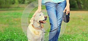 Owner woman walking with her Golden Retriever dog on leash in summer park