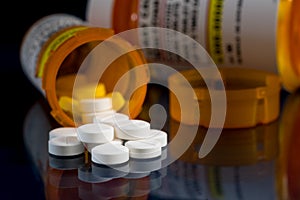 Macro of oxycodone opioid tablets with prescription bottles against dark background photo