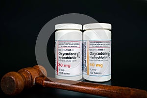 Oxycodone Hydrochloride prescription bottles isolated on black background with judge gavel infront. photo