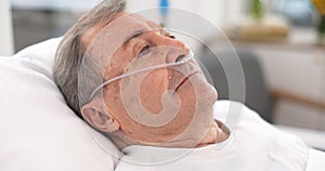 Oxygen, hospital bed and senior man with ventilation and breathing tube support in a clinic. Elderly patient, medical