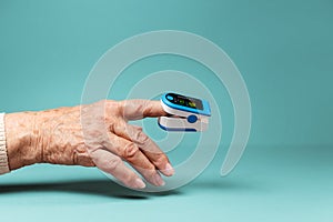 Oxymeter on the index finger of an senior woman. Hand close-up. The concept of determining oxygen saturation in blood photo