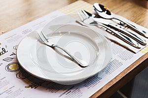 Oyster fork with cutlery: Spoon, Fork and Knife on white ceramic plate. Silver plated food ware