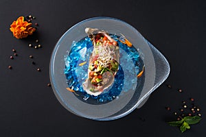 Oyster tartare. Fish delicacy on blue ice. Beautiful serving of seafood on a black background