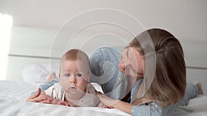 p portrait of a beautiful young Asian or Caucasian mother girl kissing her healthy newborn baby in bed with copy space