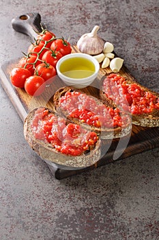Pa amb tomaquet or tomaca bread with tomato also known as pan con tomate and tostada closeup on the wooden board. Vertical photo