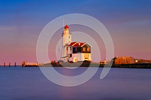 Paard van Marken, Netherlands. A lighthouse on the beach during sunset. A landmark in maritime navigation.